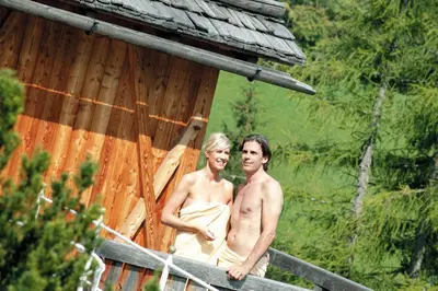 a man and woman standing on the porch of a cabin at Hotel Albion Mountain Spa Resort Dolomites in Ortisei