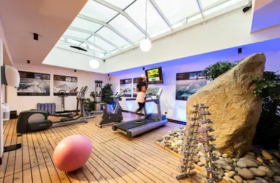 a woman running on a treadmill in a gym at Hotel Albion Mountain Spa Resort Dolomites in Ortisei