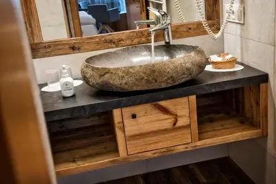a bathroom sink with a large stone bowl at Hotel Interski in Santa Cristina in Val Gardena