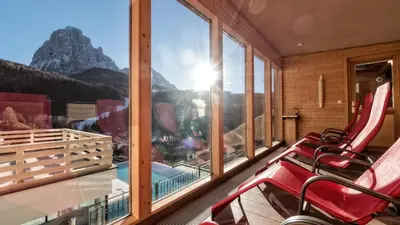 a room with chairs and a window with a mountain view at Hotel Interski in Santa Cristina in Val Gardena
