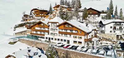 a hotel in the snow with cars parked in front of it at Hotel Interski in Santa Cristina in Val Gardena