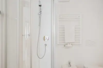 a white bathroom with a shower and a sink at Residence krUma in Valdaora