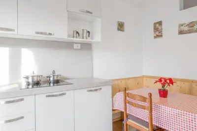 a kitchen with white cabinets and a table with a table at Residence krUma in Valdaora