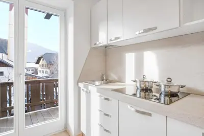 a kitchen with white cabinets and a large window at Residence krUma in Valdaora