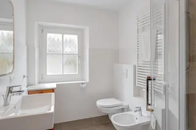 a white bathroom with a sink and a toilet at Residence krUma in Valdaora