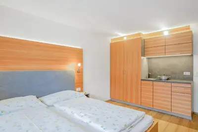 a bedroom with a large bed and a kitchen at Residence krUma in Valdaora