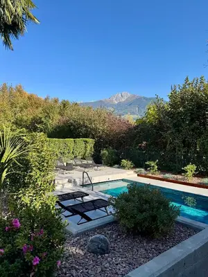 a swimming pool in a garden with a mountain in the background at Villa Ladurner in Tirolo