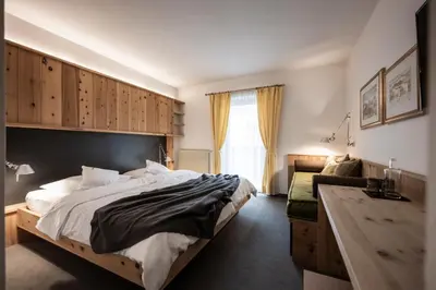 a bedroom with a large bed and a desk at Hotel & Gasthof zum Hirschen in San Genesio Atesino