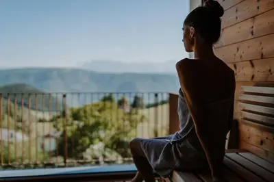 a woman sitting on a bench looking out of a window at Hotel & Gasthof zum Hirschen in San Genesio Atesino