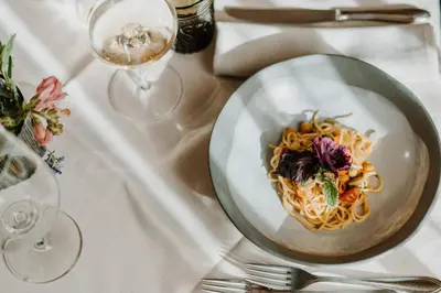 a plate of pasta on a table with wine glasses at Hotel & Gasthof zum Hirschen in San Genesio Atesino
