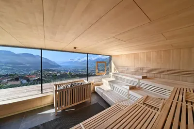 a sauna with benches and a large window at Hotel Patrizia in Tirolo