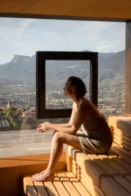 a man sitting on a bench looking out a window at Hotel Patrizia in Tirolo
