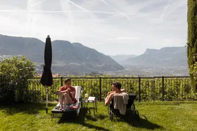 a couple of people sitting in chairs in the grass at Hotel Patrizia in Tirolo