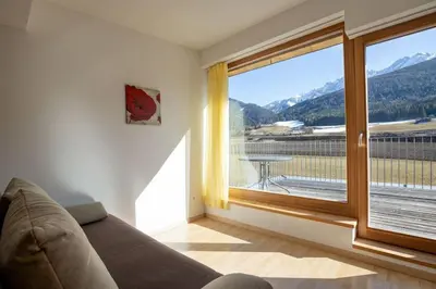 a living room with a couch and a large window at Appartements Durnbrunn in Valdaora