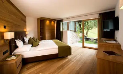 a bedroom with a bed and a tv and a window at Hotel Grien in Ortisei
