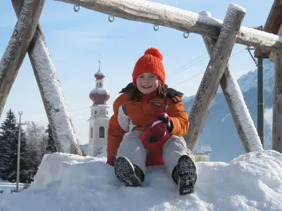 a young girl sitting on a pile of snow at Stifterhof in Villabassa