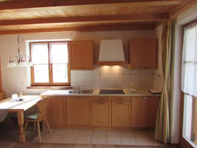 a kitchen with wooden cabinets and a table and a sink at Stifterhof in Villabassa