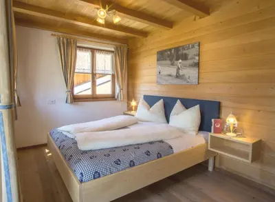 a bedroom with a bed in a wooden room at Stifterhof in Villabassa