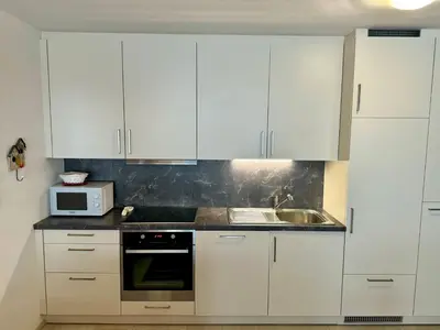 a kitchen with white cabinets and a sink and a microwave at Da Renata in Valdaora