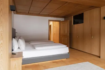 a bedroom with a bed with white sheets and wooden cabinets at Gran Tubla in Ortisei