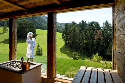 a woman standing in a window looking out at a green field at Hotel Chalet Tianes - Alpine Relax in Castelrotto