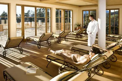 a man laying on lounge chairs in a hotel lobby at Hotel Chalet Tianes - Alpine Relax in Castelrotto
