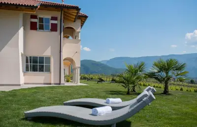 a group of lounge chairs in the grass in front of a house at Gutshof Rellich in Termeno