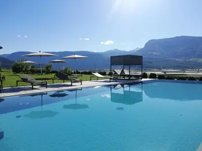 a large swimming pool with chairs and umbrellas at Gutshof Rellich in Termeno