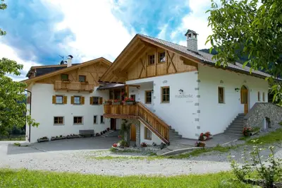 a large white house with a wooden roof at Obermoserhof in Feldthurns