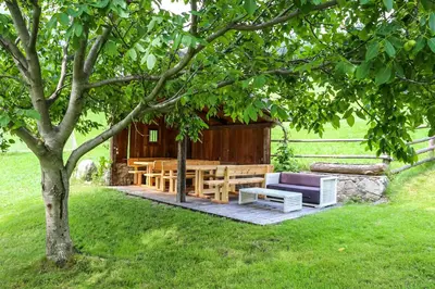 a picnic table and a couch under a tree at Obermoserhof in Feldthurns