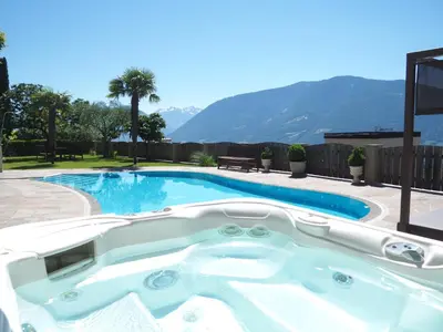 a swimming pool with a hot tub in a yard at Hotel-Garni Ehrenfels in Schenna