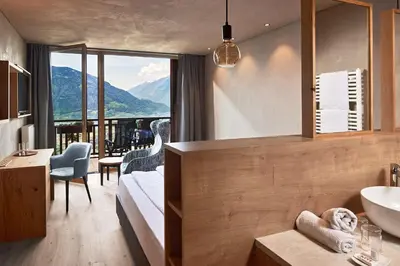 a bathroom with a bed and a sink in a room at Hotel-Garni Ehrenfels in Schenna