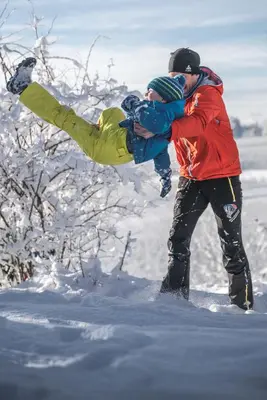 a man holding a child in the snow at BUEHLERHOF Urlaub mit Kind & Hund, Obst-& Weingut, Brixen in Rosa