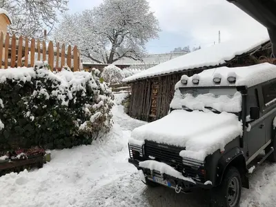 a truck covered in snow next to a fence at BUEHLERHOF Urlaub mit Kind & Hund, Obst-& Weingut, Brixen in Rosa