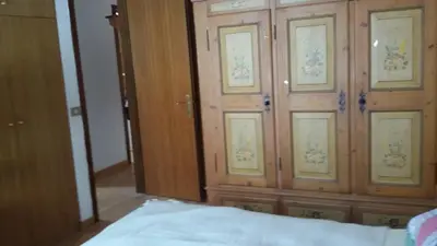 a bedroom with a wooden cabinet with doors and a bed at CasaMau Trilo in Campitello di Fassa