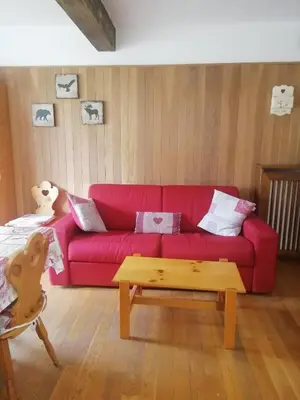 a living room with a red couch and a coffee table at CasaMau Trilo in Campitello di Fassa