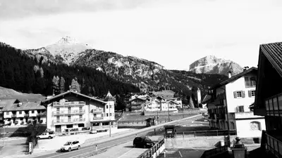 a black and white photo of a town with mountains at CasaMau Trilo in Campitello di Fassa