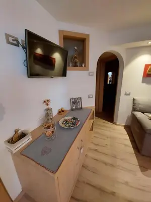 a kitchen with a counter with a television on the wall at Casa Rita in Tesero