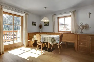 a kitchen with a table and chairs and windows at Ciasa Medalghes in San Martino in Badia