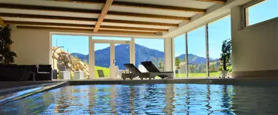 a swimming pool with chairs in a room with windows at Agriturismo Anví in Badia