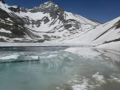 a body of water in front of a snow covered mountain at Plattnerhof in Fundres