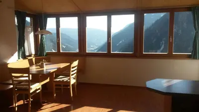 a dining room with a table and chairs and windows at Plattnerhof in Fundres