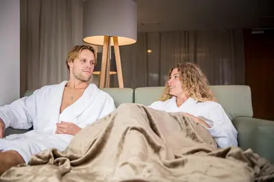 a man and a woman sitting on a couch at Kronplatz-Resort Hotel Kristall in Valdaora