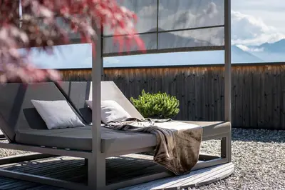 a bed sitting on a patio with a plant at Kronplatz-Resort Hotel Kristall in Valdaora