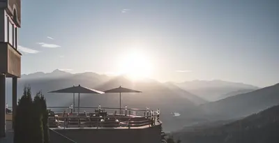 a restaurant with tables and umbrellas in the mountains at Kronplatz-Resort Hotel Kristall in Valdaora