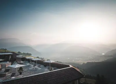 a view of the mountains from a hotel with tables and umbrellas at Kronplatz-Resort Hotel Kristall in Valdaora