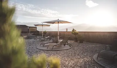 a group of chairs and umbrellas on a patio at Kronplatz-Resort Hotel Kristall in Valdaora