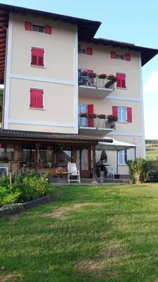 a large white building with red windows and a lawn at Casa da Aldo in Castelfondo