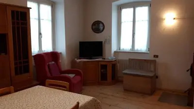 a living room with a television and two chairs at Casa da Aldo in Castelfondo