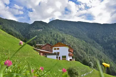 a building on the side of a green hill at Obererhof in SantʼAndrea in Monte